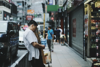 男子斜靠灰色钢栅栏的浅层摄影